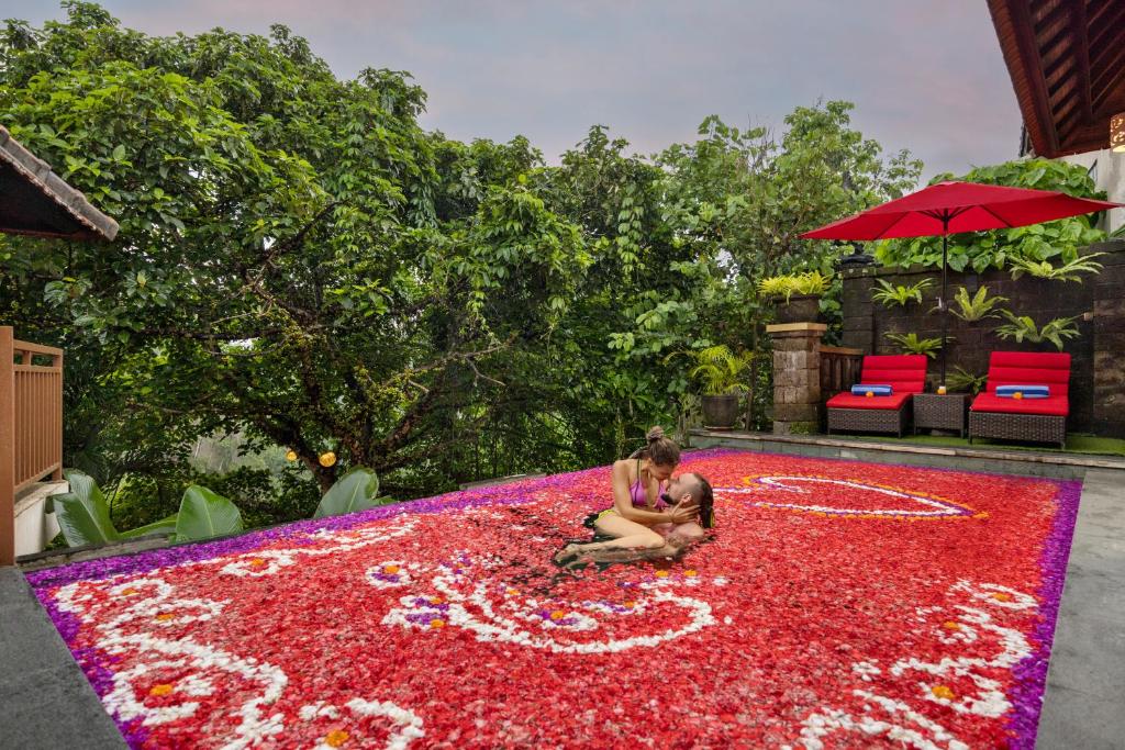 una mujer sentada en una gran alfombra de flores en Griya Shanti Villas & Spa, en Ubud