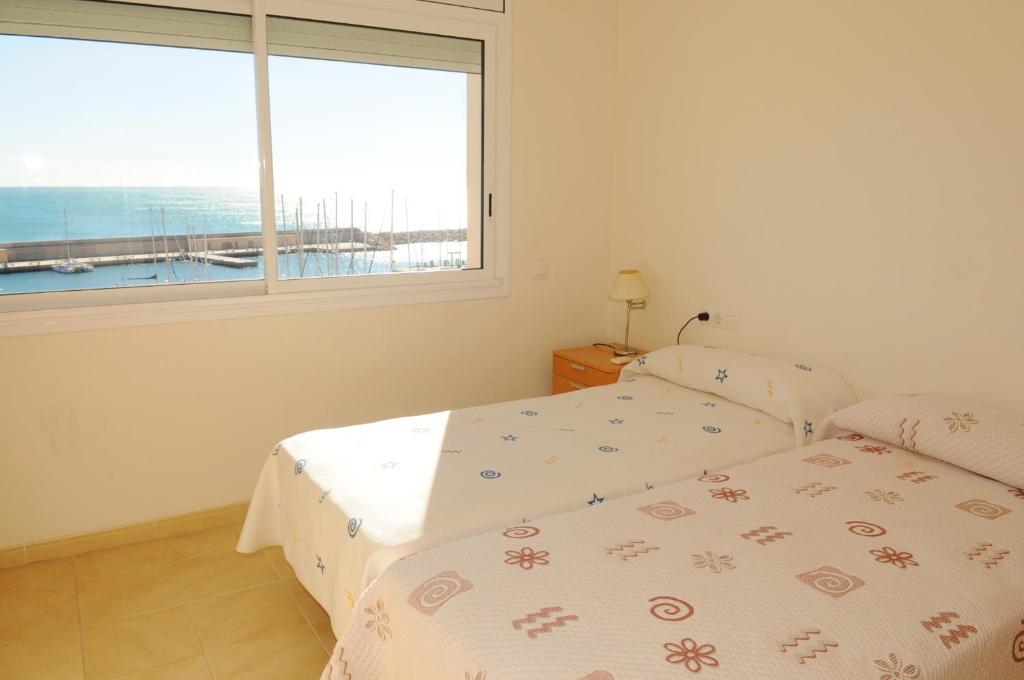 a bedroom with two beds and a large window at Residencial Marina de Port in L'Ametlla de Mar