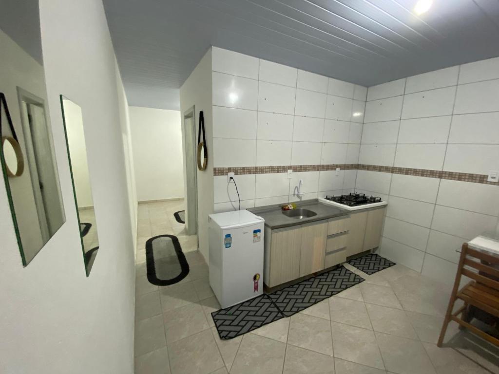 une petite cuisine avec un évier et un réfrigérateur dans l'établissement Casa perto da praia em Itapema, à Itapema