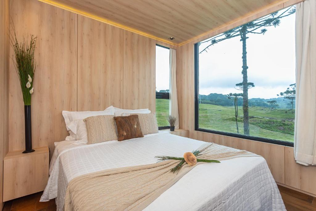 ein Schlafzimmer mit einem Bett mit einem großen Fenster in der Unterkunft Brumas Casa de Campo - Cambará do Sul in Cambará