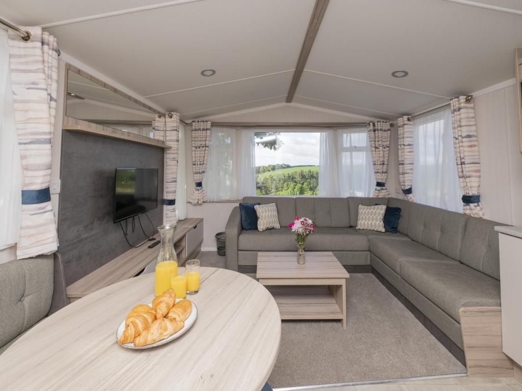 a living room with a table and a couch at Suncrest Plus Caravan by Belvilla in Looe