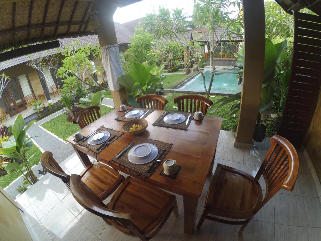 a wooden table and chairs with a table and a pool at Chez Ida in Ubud