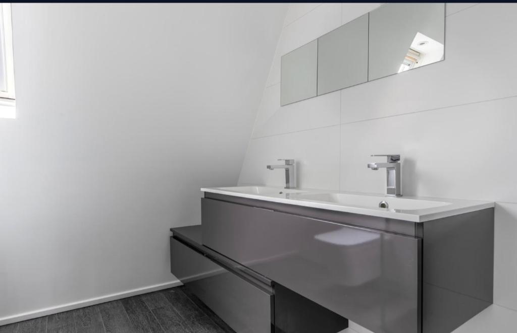 une salle de bain blanche avec un lavabo et un miroir dans l'établissement Angel, à Lagny-sur-Marne