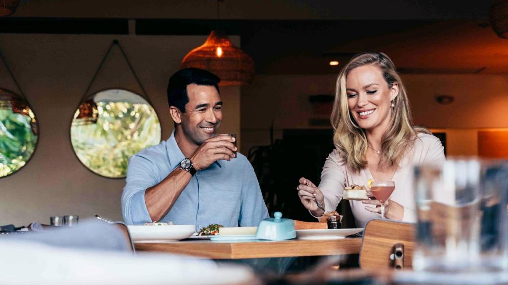 a man and woman sitting at a table in a restaurant at Lotus Honolulu at Diamond Head in Honolulu