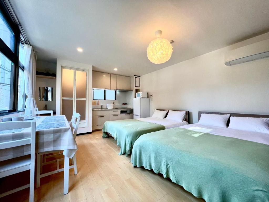 a bedroom with two beds and a desk and a kitchen at Asakusa Hana hostel in Tokyo