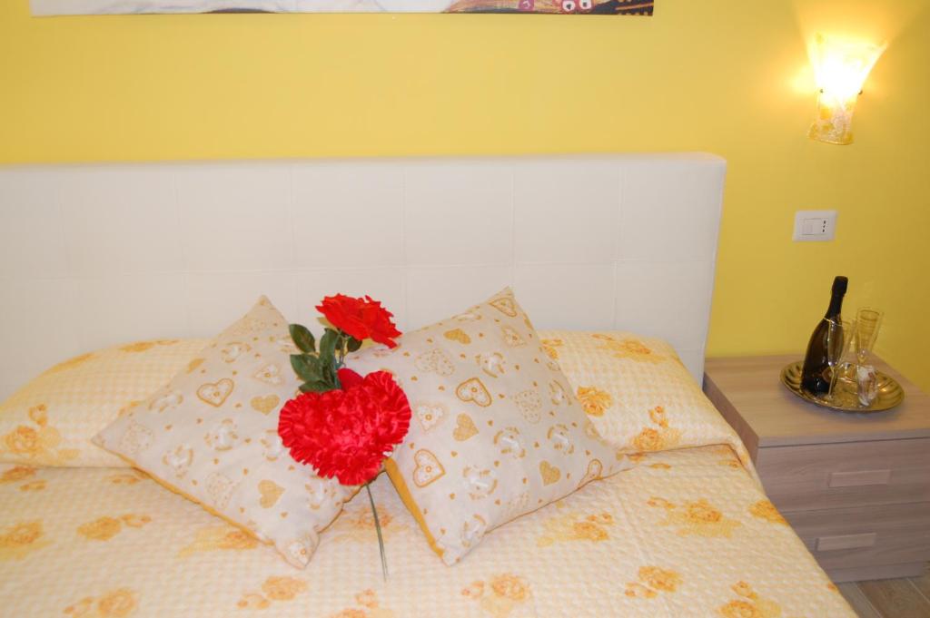uma cama com duas almofadas com uma flor vermelha em B&B Il Salice em Borghesiana 