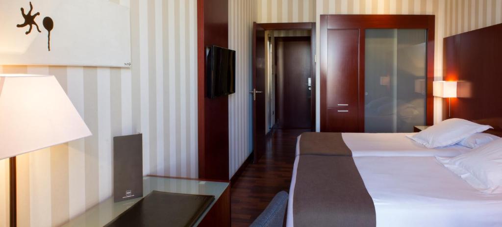 a hotel room with a bed and a desk with a lamp at Zenit Valencia in Valencia