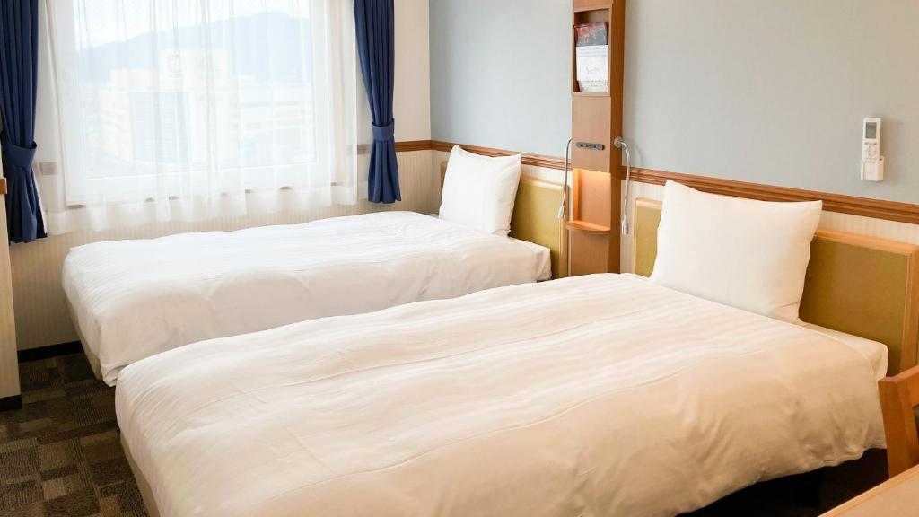 Postel nebo postele na pokoji v ubytování Toyoko Inn Tsuruga Ekimae