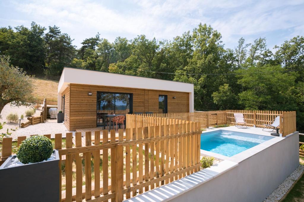 une maison avec une clôture en bois et une piscine dans l'établissement La BOOA - Écolodge en Ardèche - Piscine privée - Ecolodgîte, à Ozon