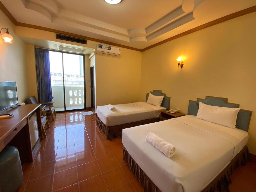 a hotel room with two beds and a television at SR Hotel in Ban Tha Kup