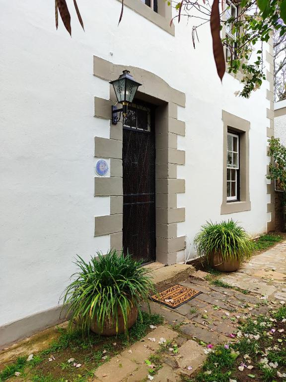 a white building with a black door and some plants at The Writer's House in Bedford