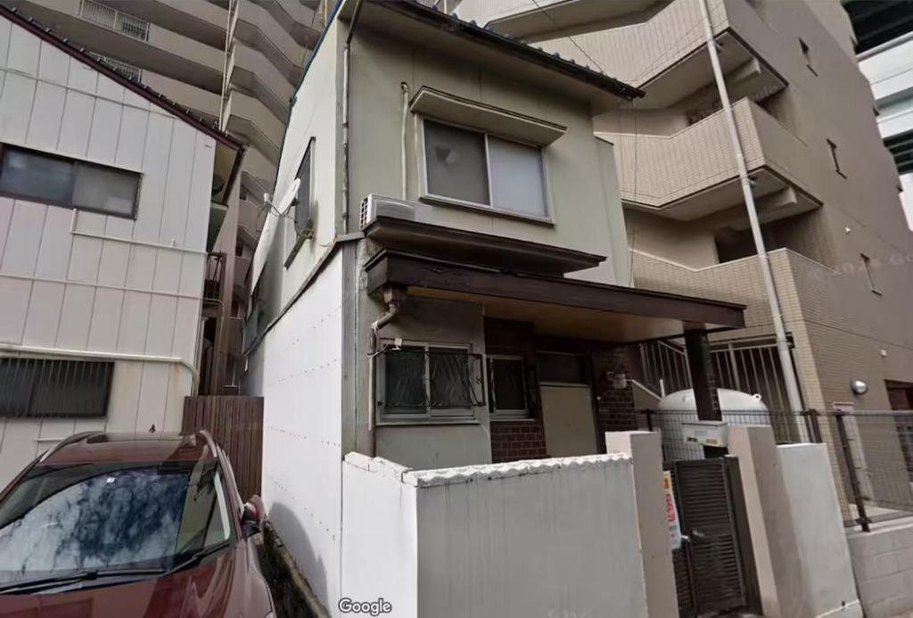 a house being built with a car parked in front of it at 博多駅徒歩8分の古民家ホテル in Fukuoka