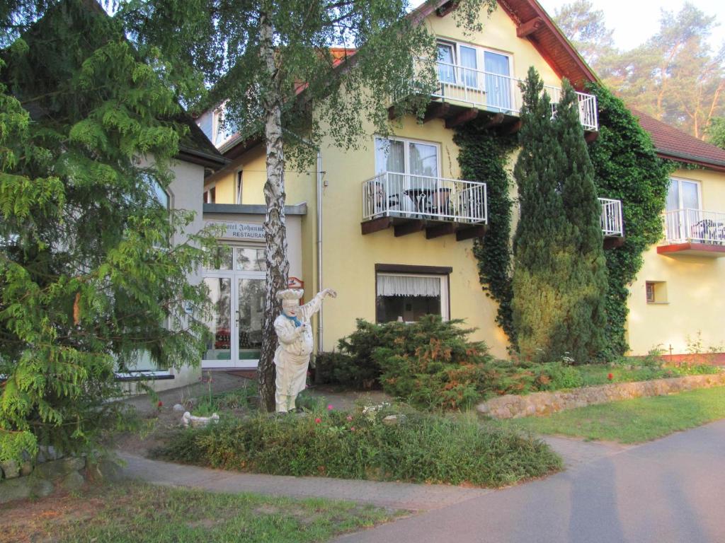 a woman standing in front of a house at Hotel & Waldrestaurant Johannesruh in Wesenberg