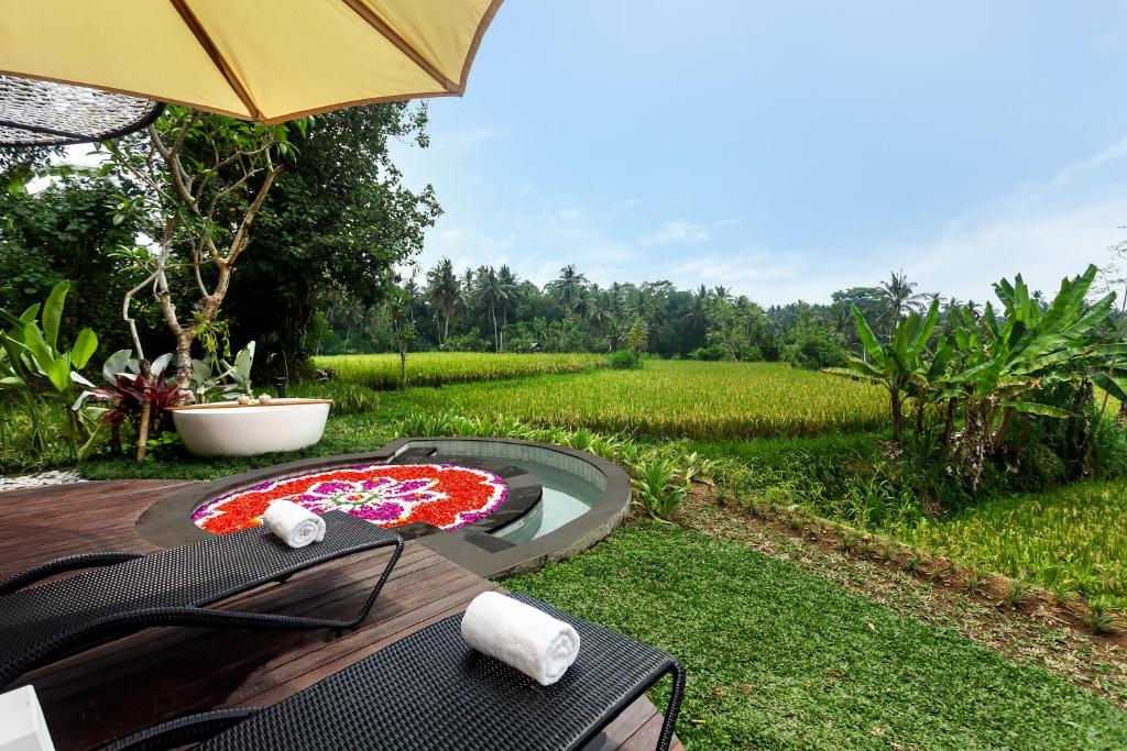 een tafel met een paraplu naast een veld bij The Pulu Villas by GenuineHost in Ubud
