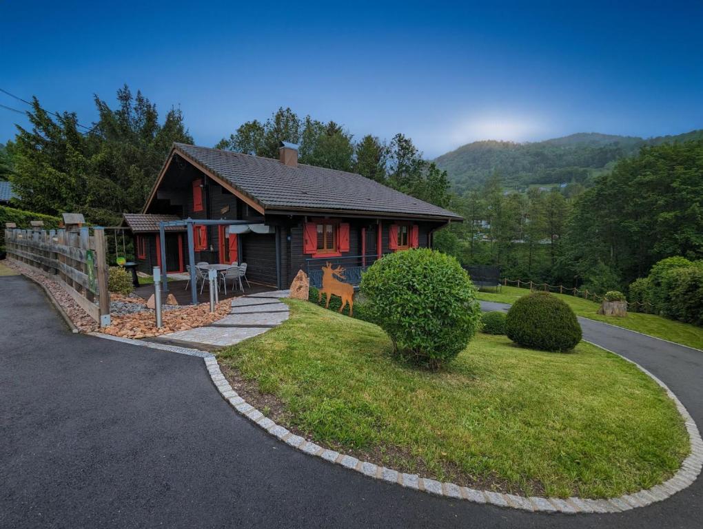 une petite maison rouge sur une route à côté d'une maison dans l'établissement Chalet Les Volets Rouges, à Cornimont