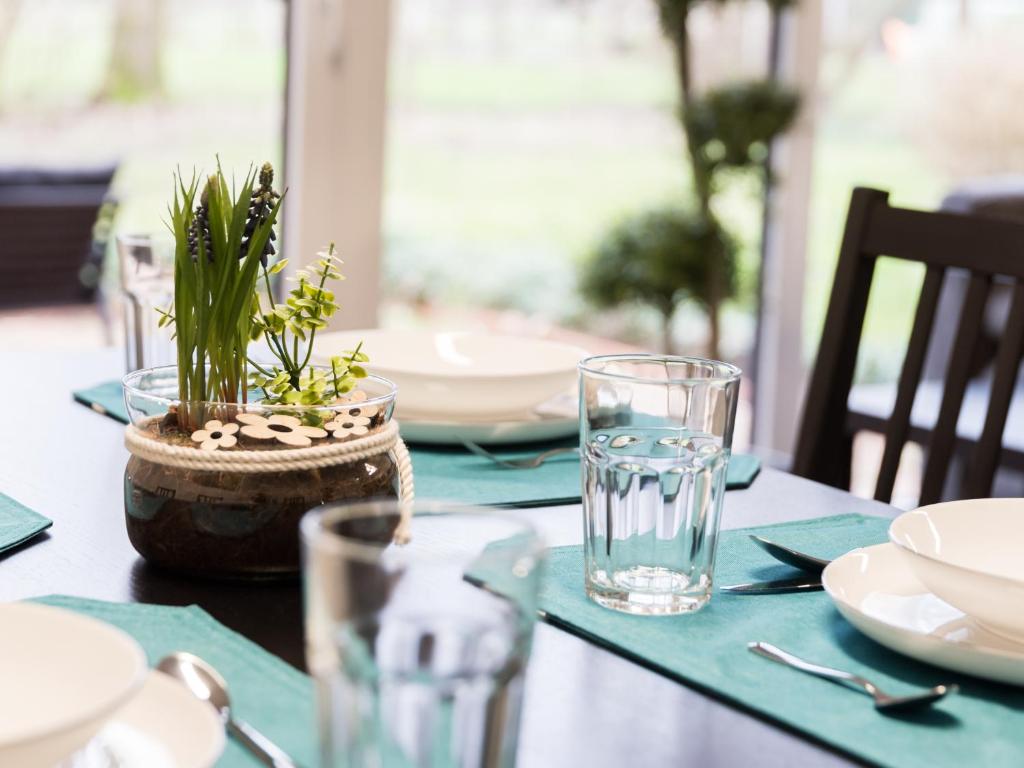 a table with plates and glasses and a plant on it at Gästehaus Moorblick in Osten