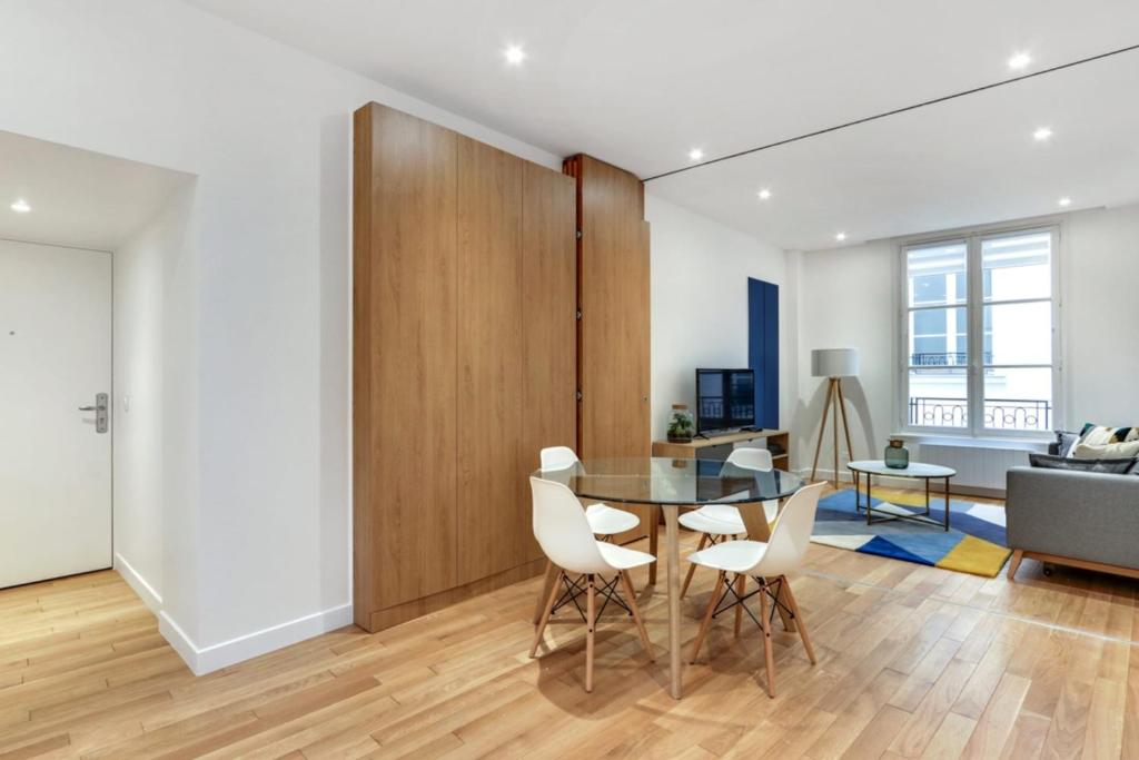 une salle à manger avec une table en verre et des chaises blanches dans l'établissement Flexliving - T2 - Bretagne, à Paris