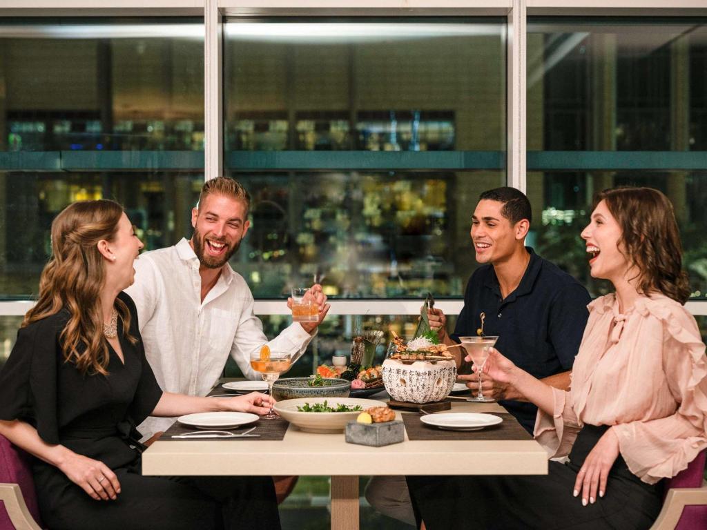 a group of people sitting around a table eating food at Pullman Doha West Bay in Doha
