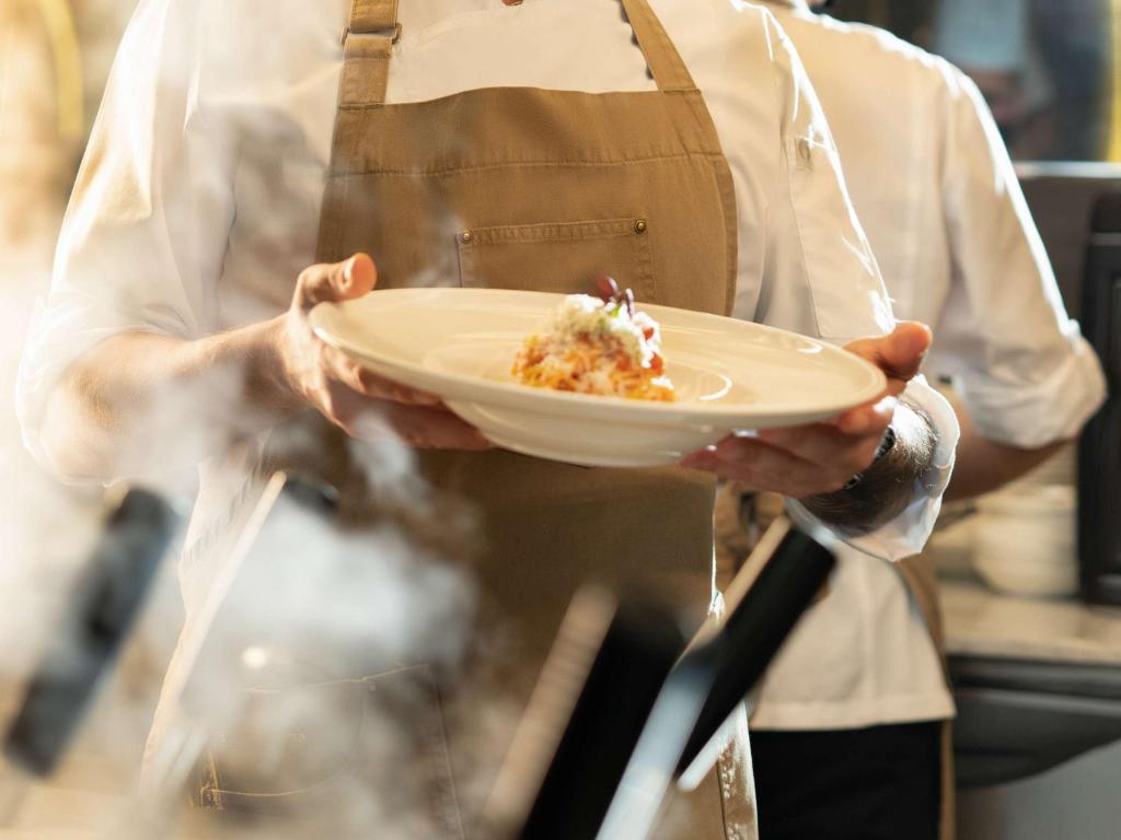 a chef is holding a plate of food at Pullman Doha West Bay in Doha