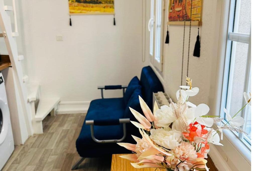 un salon avec une chaise bleue et une table fleurie dans l'établissement Dream Dwell Paris-Apart at the heart of 3e Marais District, à Paris