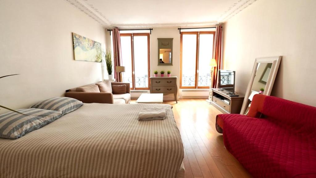 - un salon avec un lit et un canapé rouge dans l'établissement 02 grand studio near montorgueil, à Paris