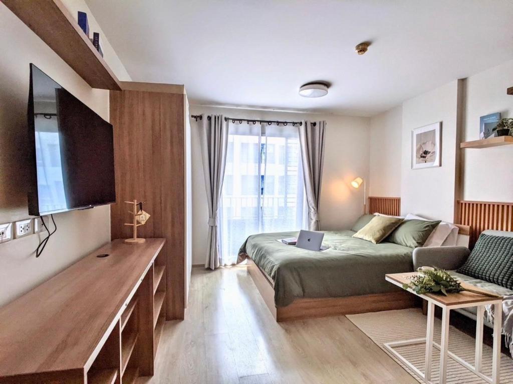 a bedroom with a bed and a couch and a tv at Elio Sukhumvit 64: Chic Space in Bangkok