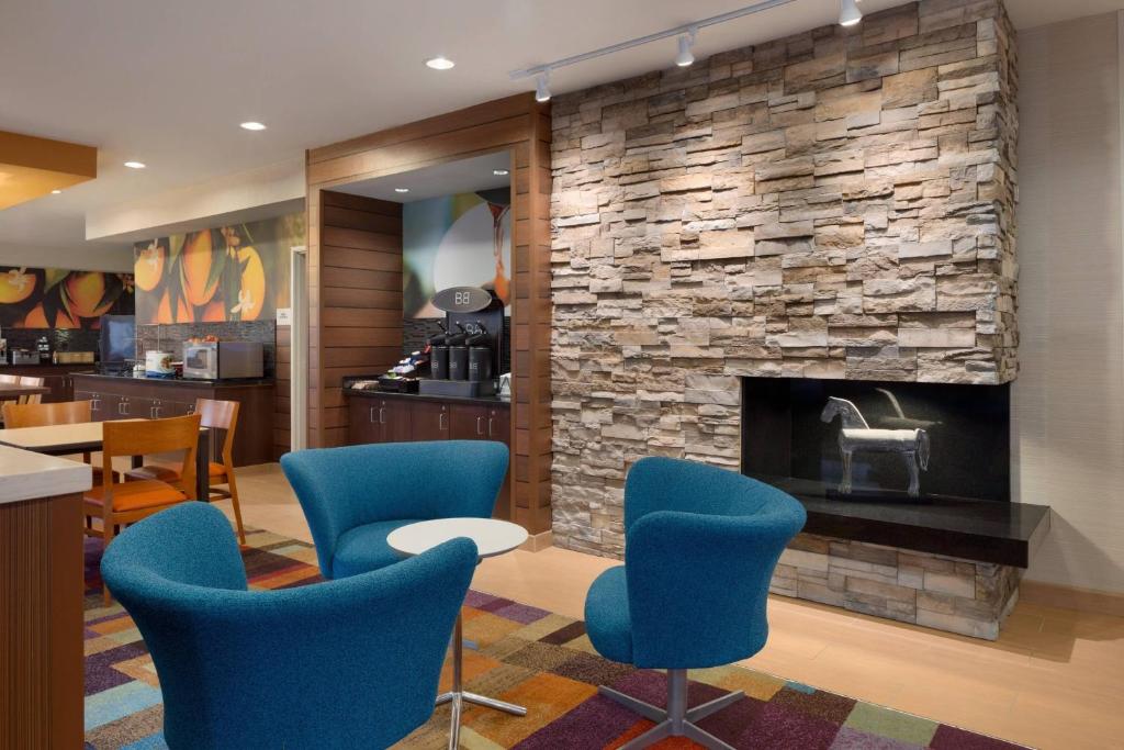 a lobby with blue chairs and a stone fireplace at Fairfield Inn & Suites Youngstown Boardman Poland in Poland