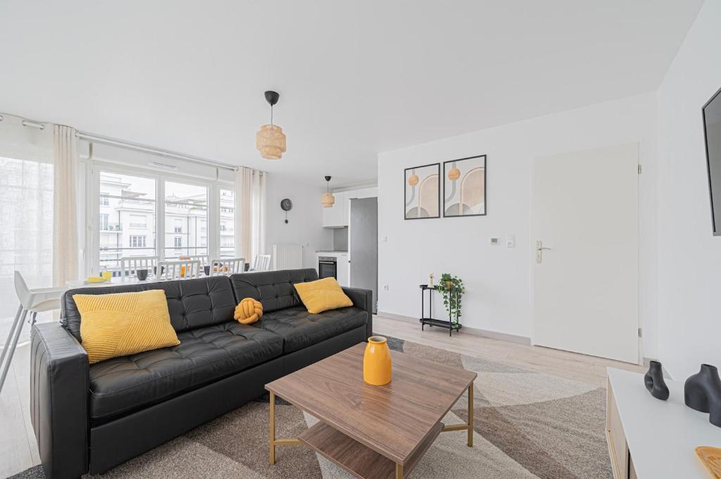 un salon avec un canapé noir et une table dans l'établissement Elegant Disney Paris apartment for 6, à Chessy