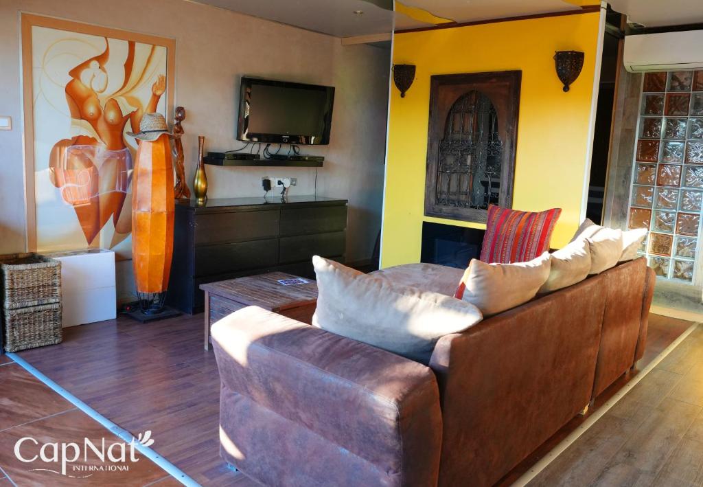 - un salon avec un canapé brun et une télévision dans l'établissement CapNat - Village Naturiste - Port Nature - Villa Marrakech, au Cap d'Agde