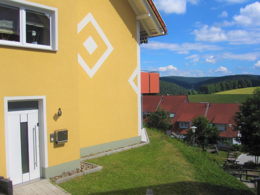 a yellow house with a white door and a view at Fewo Furtwangen in Furtwangen