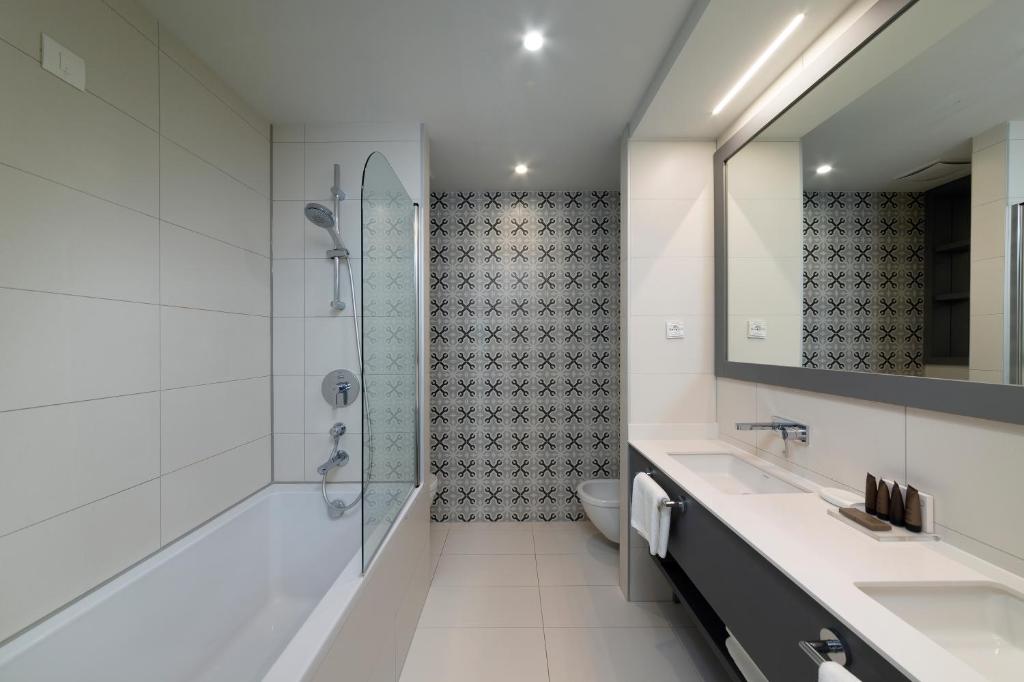 a white bathroom with a shower and a sink at Royal Neptun Hotel in Dubrovnik