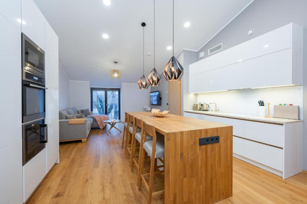 a kitchen with white cabinets and a kitchen island with a table at Modern city center apartment in Tartu
