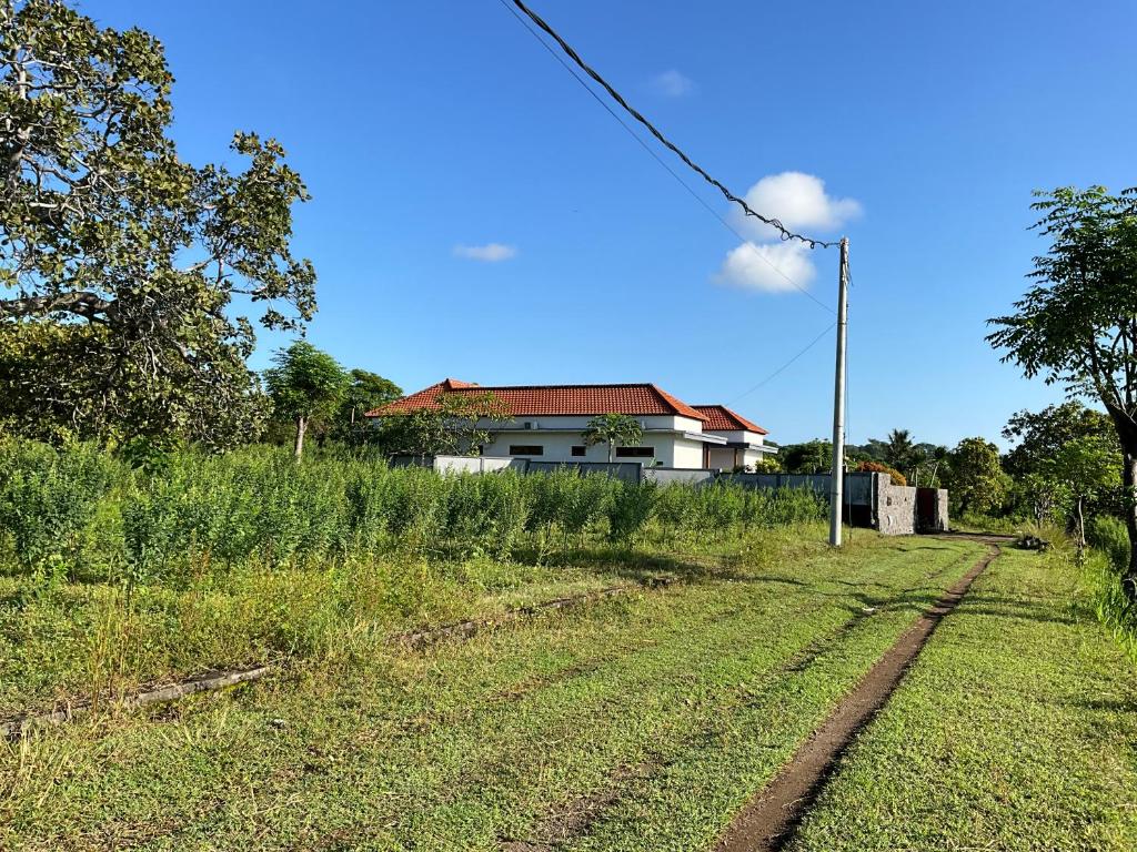 a house in a field next to a dirt road at Villa Rosa East Bali in Karangasem