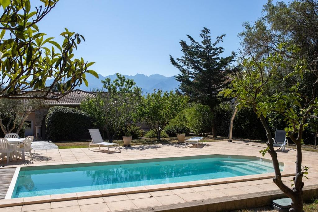 - une piscine dans une cour avec une terrasse et des arbres dans l'établissement Charmante villa avec piscine proche ville et plage, à Calvi