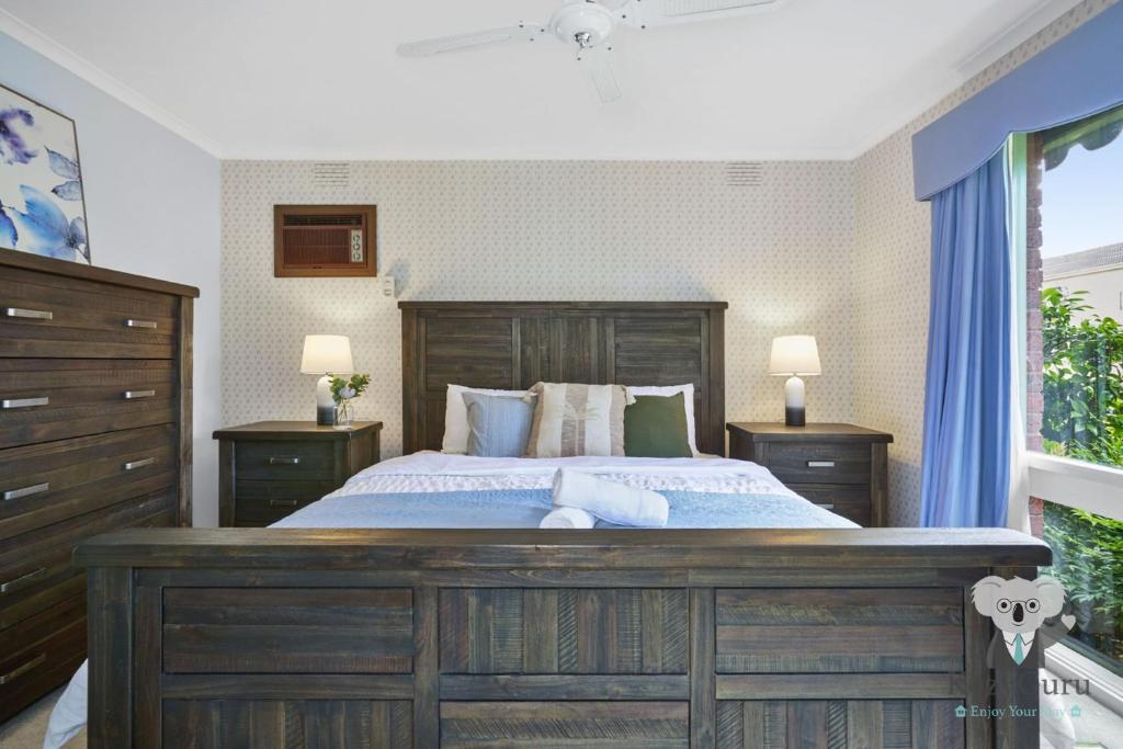 una camera da letto con un grande letto in legno con due comodini di KozyGuru Glen Waverley Family Home & Backyard a Glen Waverley
