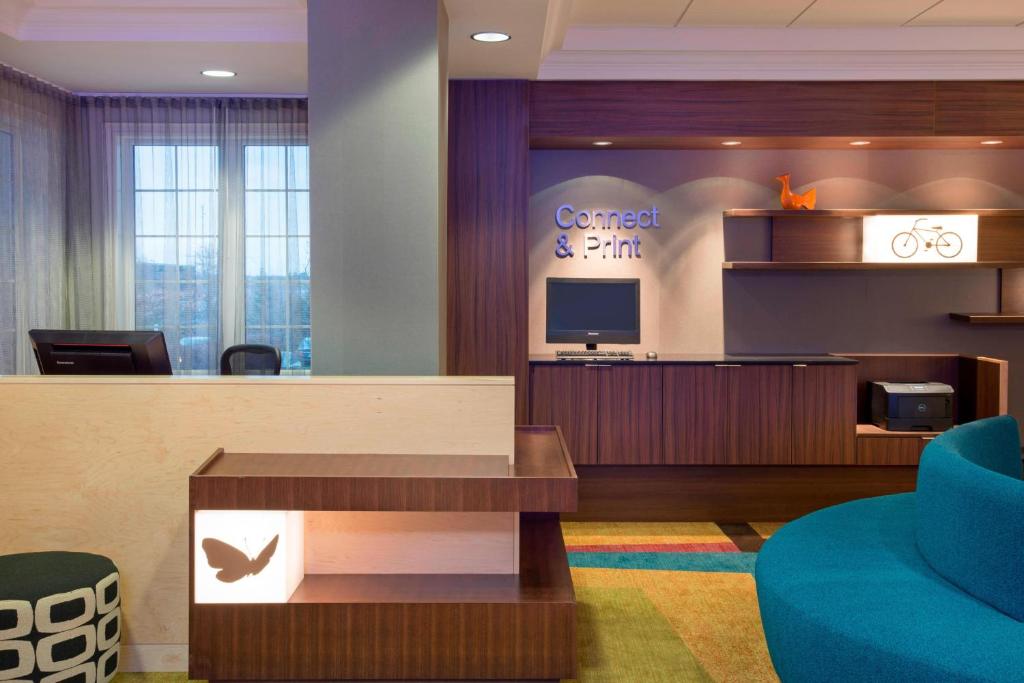 a hotel lobby with a waiting area with a sign that reads correct and pain at Fairfield Inn & Suites by Marriott Ottawa Kanata in Ottawa