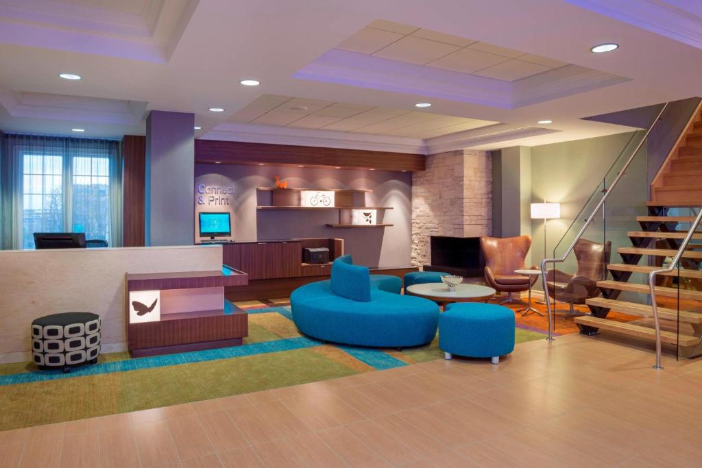 a lobby with blue chairs and tables and stairs at Fairfield Inn & Suites by Marriott Ottawa Kanata in Ottawa