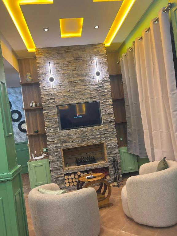 a living room with a fireplace with two chairs and a tv at Vintage Green House in Fez