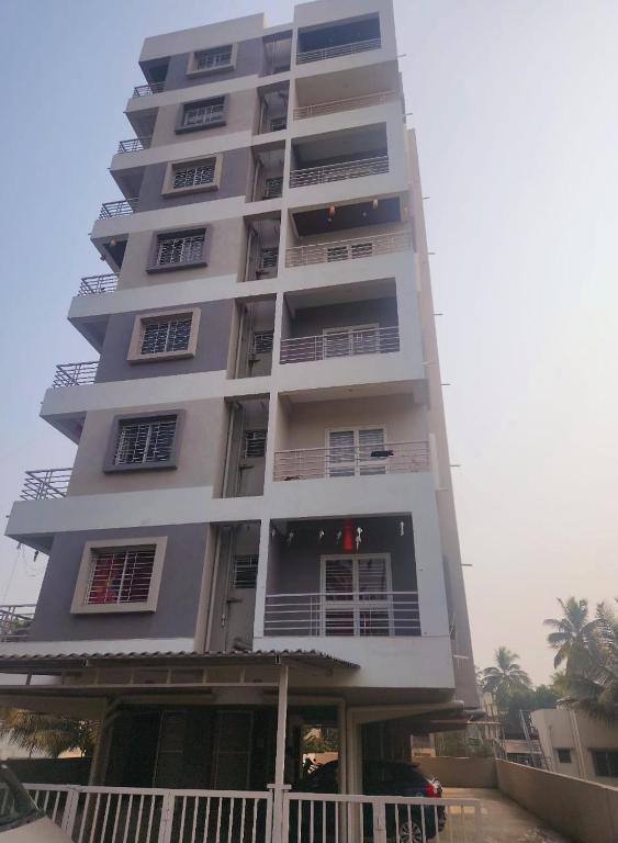 a tall white building with balconies on it at Whispering Wind Homestay in Kolhapur