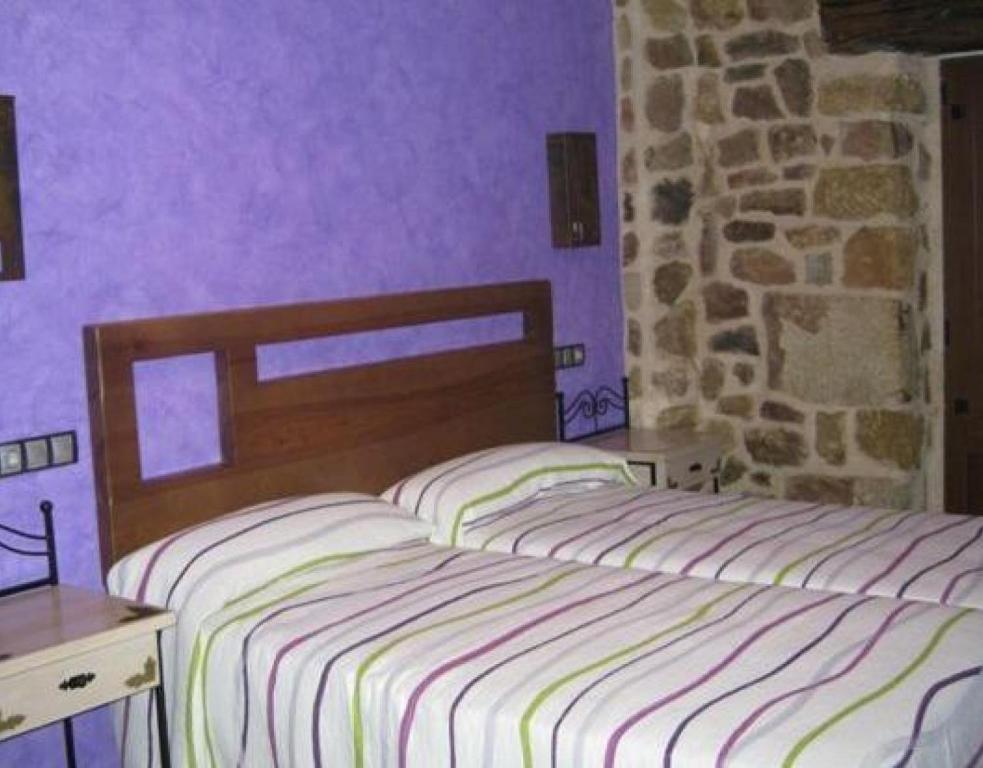 a bedroom with two beds and a stone wall at La Botería in Salas de los Infantes
