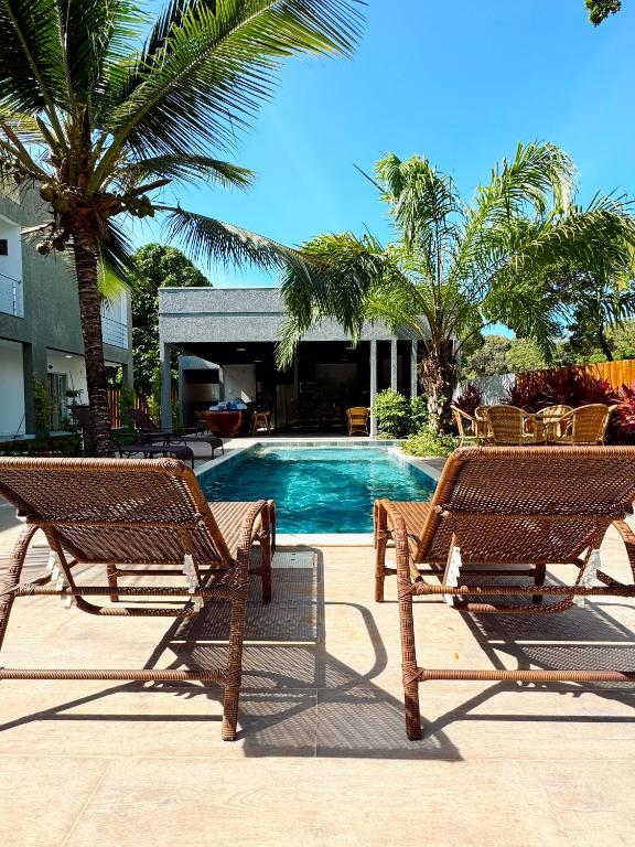 two wooden benches sitting next to a swimming pool at Pousada Sky Dream Beach Mutá Frente Mar By LVF in Porto Seguro