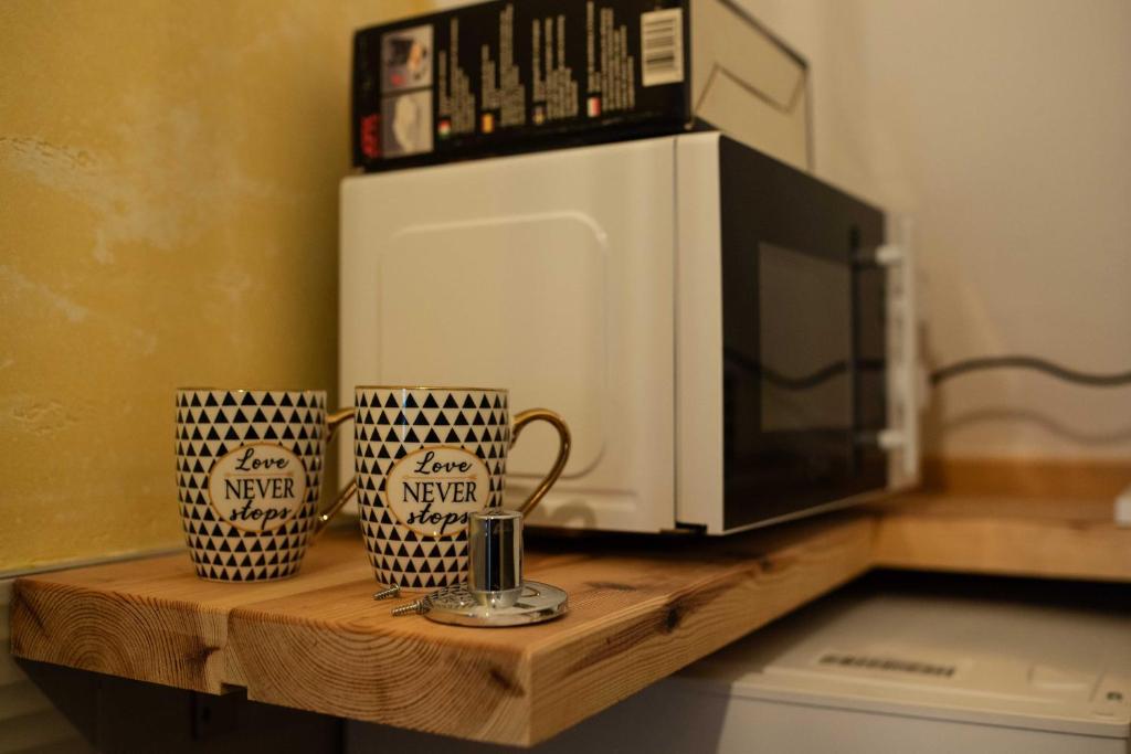 a microwave and two coffee mugs on a wooden shelf at Apartman Crni bor 2 Tara in Kaludjerske Bare