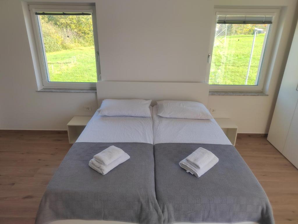 two beds in a room with two windows at Studio Apartma KIMI in Nova Gorica