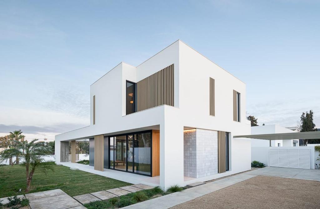 ein weißes Haus mit schwarzen Fenstern in der Unterkunft Hostidy Villa Horacia Resort in Sanlúcar de Barrameda