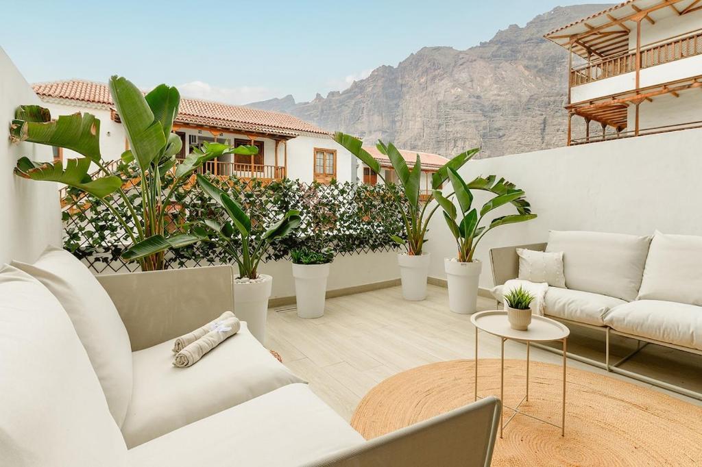 een woonkamer met witte meubels en potplanten bij Home2Rest at Los Gigantes - 1 min to beach, restaurants, city center - 1bdr in Acantilado de los Gigantes