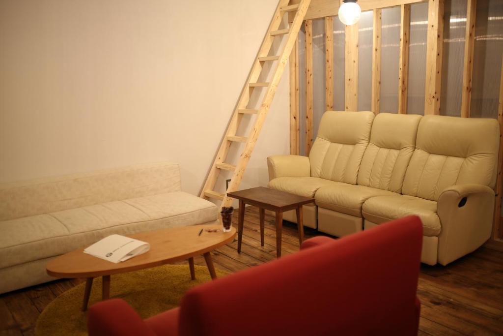 a living room with a couch and a ladder at Guest House MARUYA in Atami