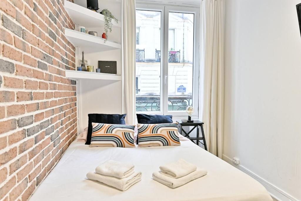 un lit dans une chambre avec un mur de briques dans l'établissement Small, cozy and centrally #marsh studio - III, à Paris