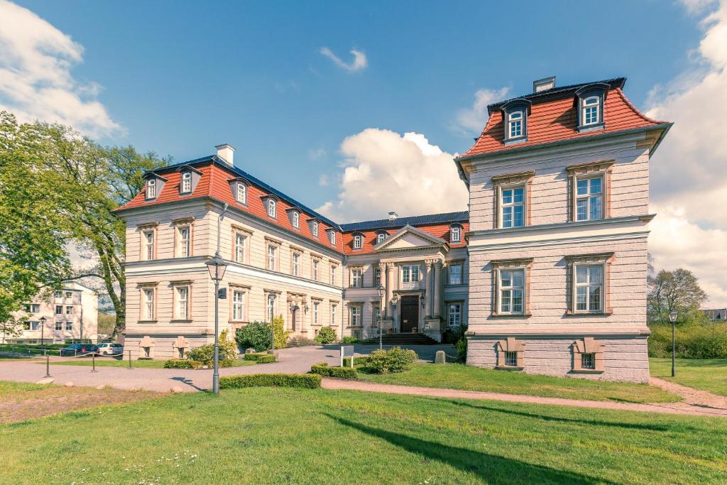 duży biały budynek z czerwonym dachem w obiekcie Hotel Schloss Neustadt-Glewe w mieście Neustadt-Glewe