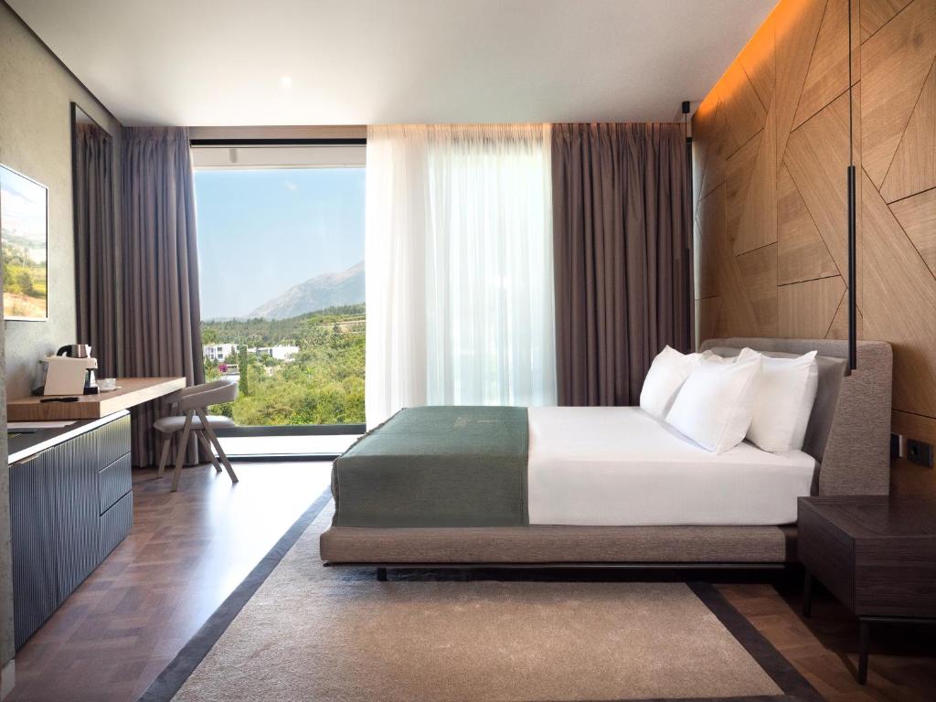a bedroom with a bed and a large window at La Brisa Boutique Hotel in Dhërmi