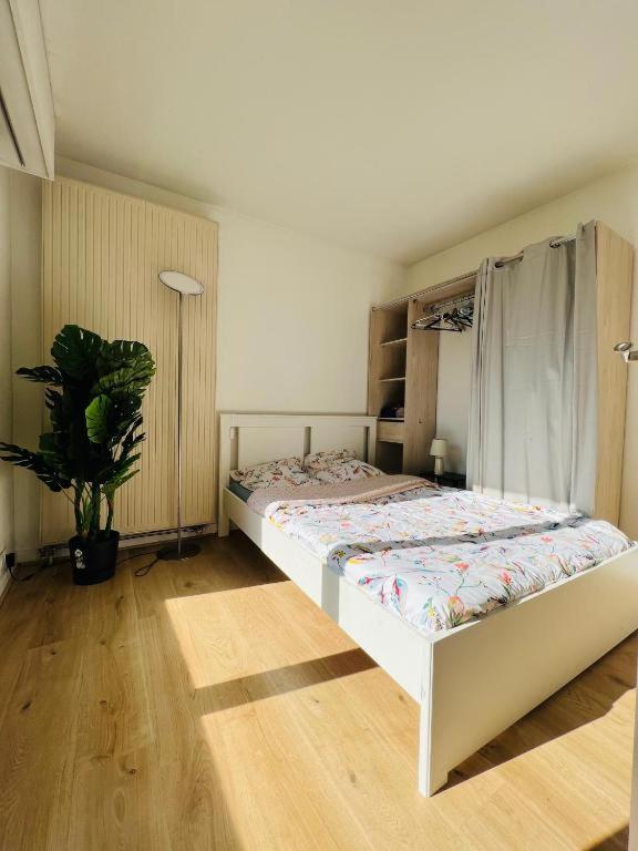 une chambre avec un lit et une plante en pot dans l'établissement Charmant appartement en plein centre ville de Nogent sur Marne, à Nogent-sur-Marne